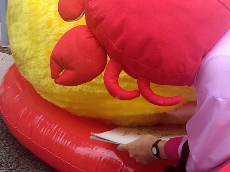 プク丸ちゃんの足元から色紙を投入するかにこ隊長